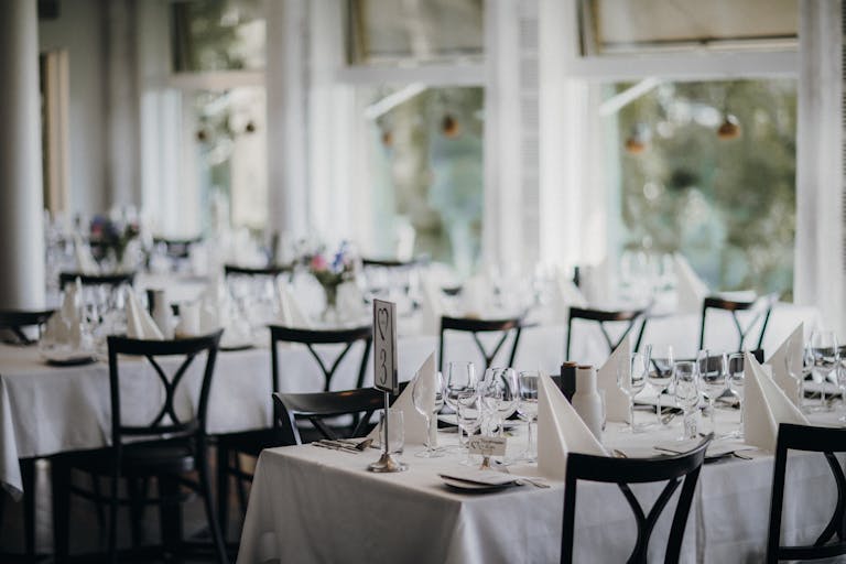 Beautifully set dining tables, perfect for a wedding reception or formal dinner event, captured indoors.