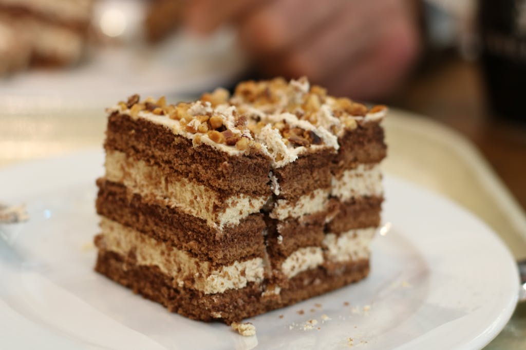 Close-up of a decadent coffee and walnut layered cake slice on a plate.
