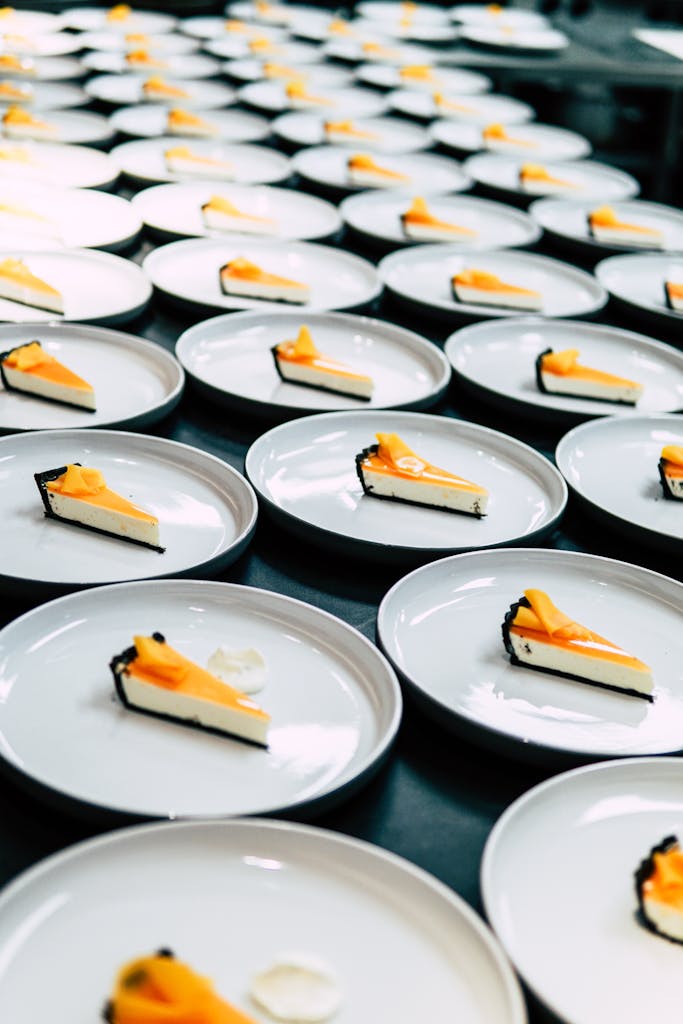 Numerous plates with slices of cheesecake neatly arranged in a row, showcasing a delicious dessert presentation.