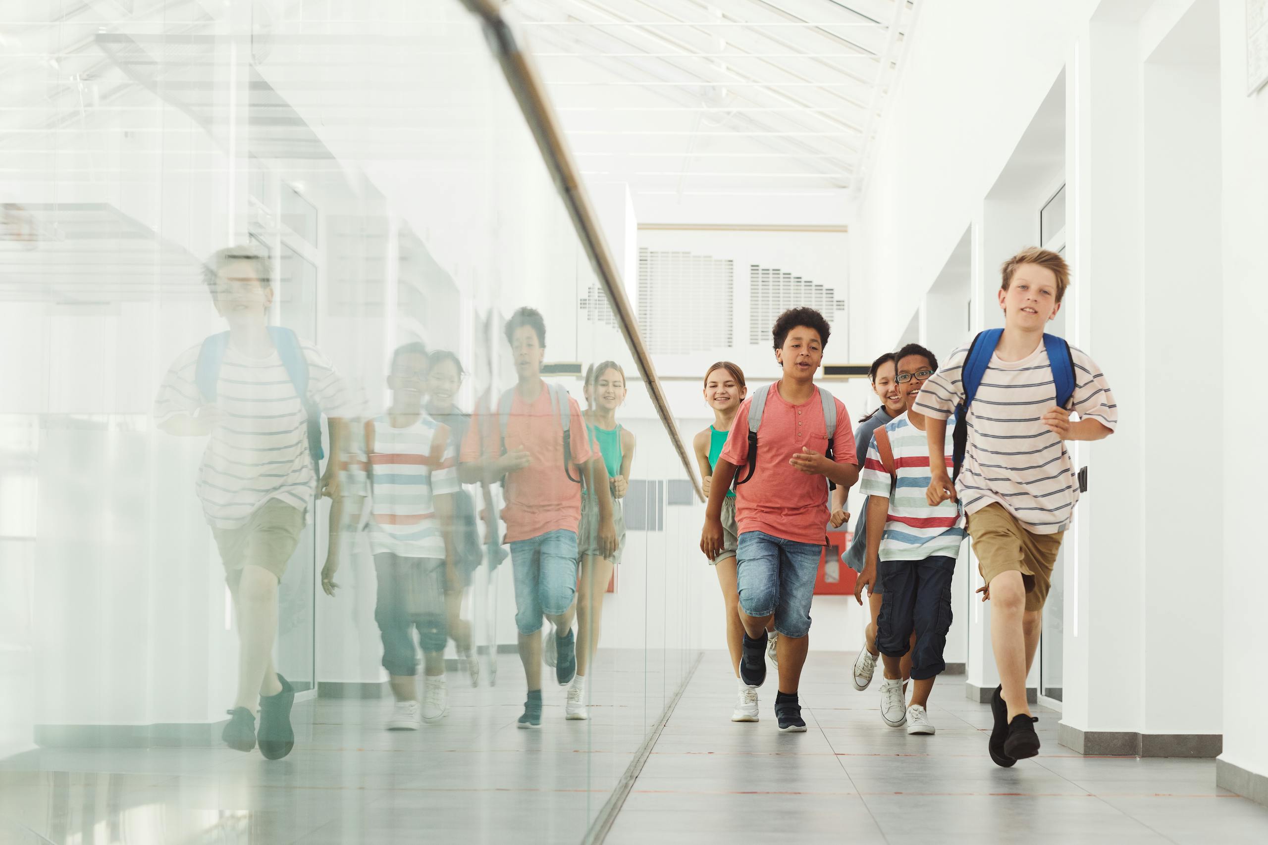 Group of diverse kids joyfully running in a bright school hallway.